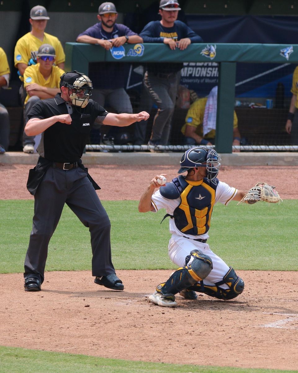 Plate umpire signaling a called strike as the catcher holds the ball